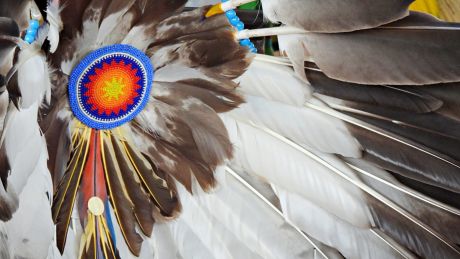 Gros plan sur un costume traditionnel autochtone orné de plumes d'aigle et de perles colorées.